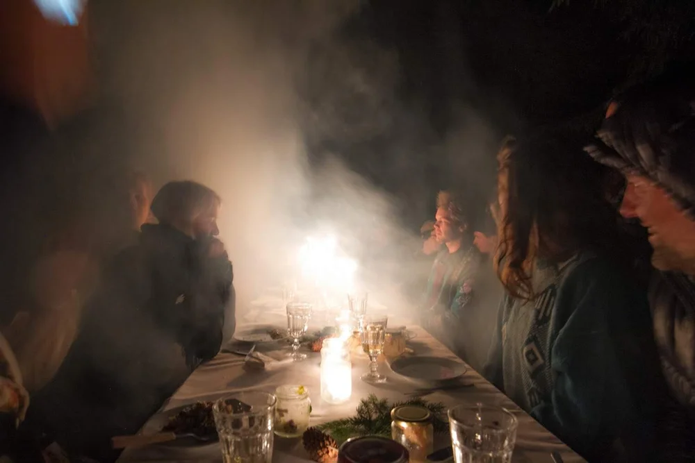 A candlelit dinner table in a smoky room
