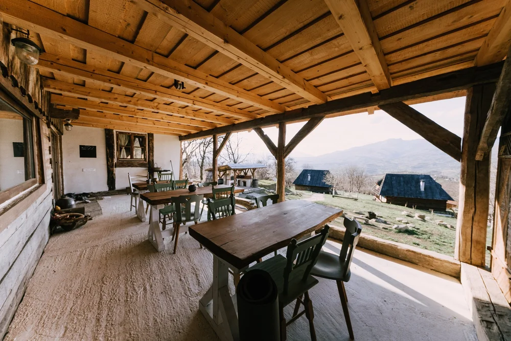 A covered dining terrace with long wooden tables